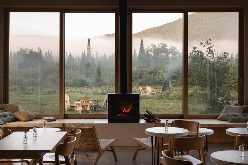 Cafe interior with wooden furniture, gas stove and large windows overlooking a grassy hill