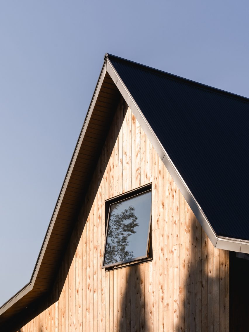 Close-up of the top of a pitched roof with a square window and timber-clad facade