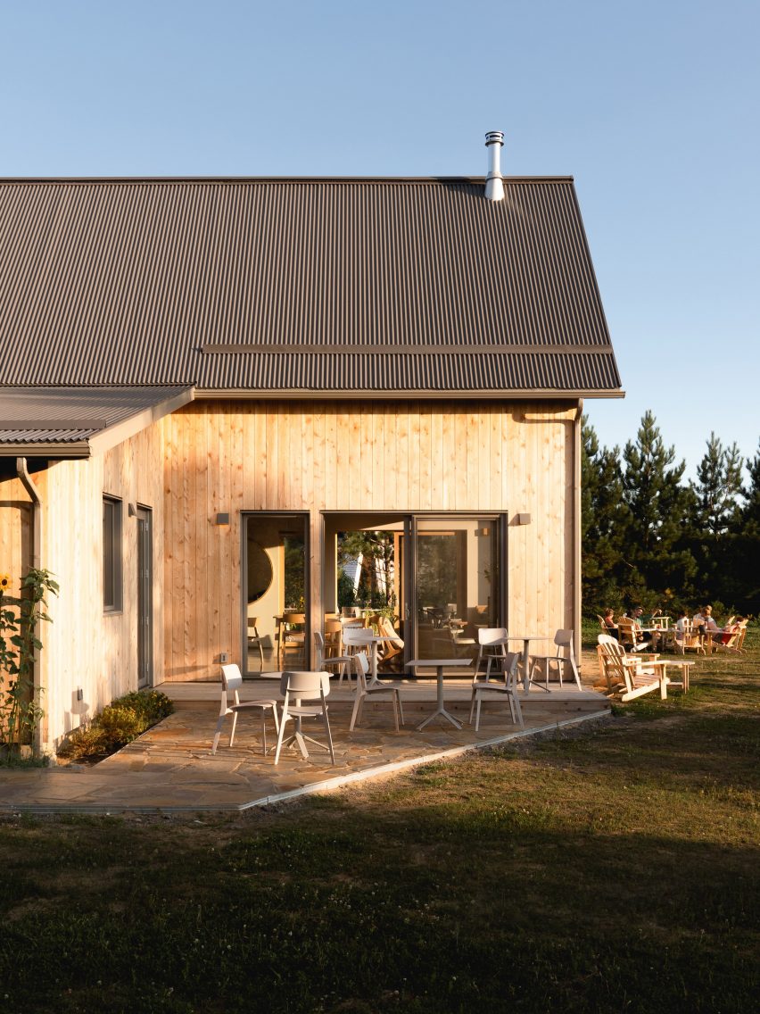 Exterior of a barn-style cafe with timber cladding, charcoal steel roof and outdoor seating