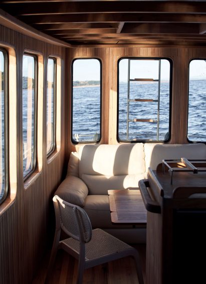 Sun with couch and bridge latter through window inside wooden boat