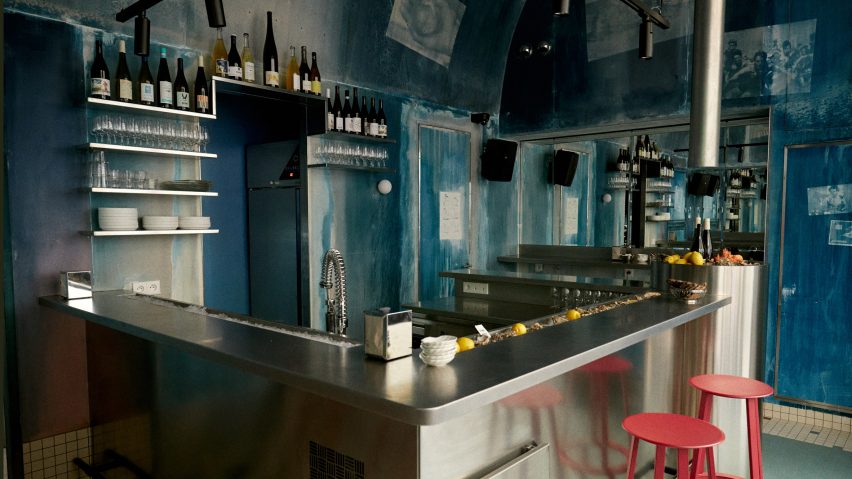 Oyster bar featuring coral-coloured stools and stainless steel countertop