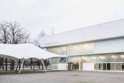 Photograph of low-slung white building with glazing with canopy-like entrance walkway