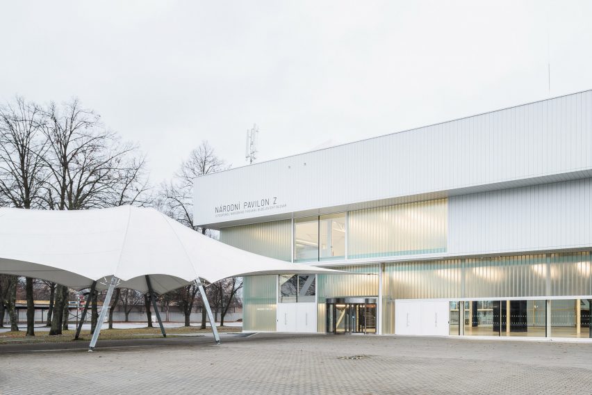 Photograph of low-slung white building with glazing with canopy-like entrance walkway