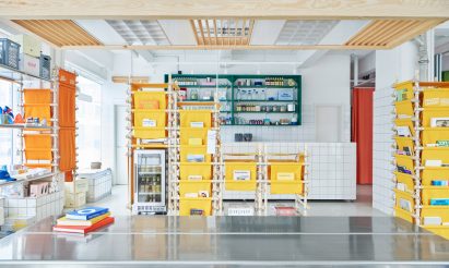 Photo of the central metal table on the ground floor of Space10's headquarters showing the details of a lighting feature made of upcycled metal components in a wooden frame hanging overhead