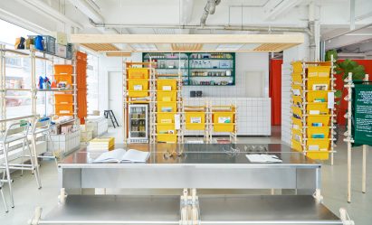A photo of the interior of the ground floor of Space10's headquarters, with a metal communal table in the centre with metal accessories that hold pensat 