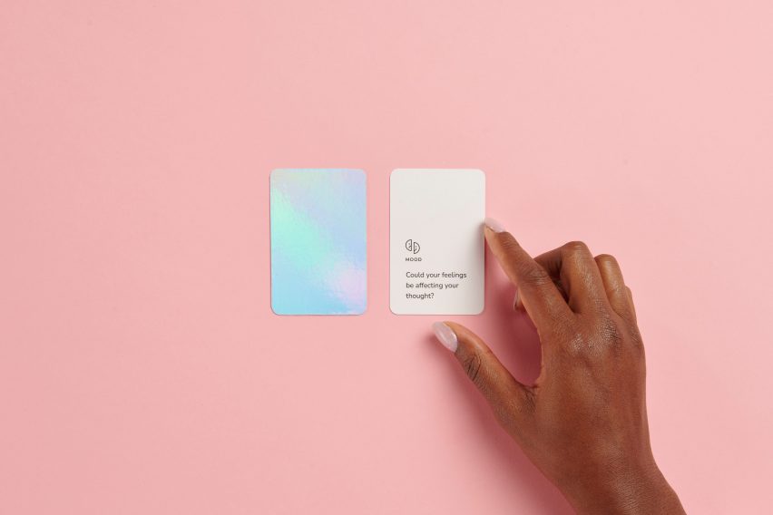 A hand fingers a small card with text that reads "could your feelings be affecting your thought?"