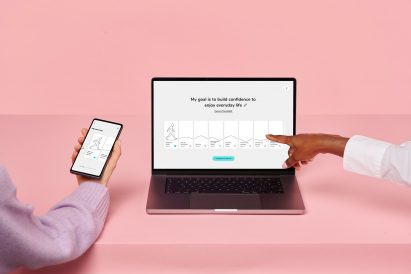 Two people sit at a laptop screen that reads "my goal is to build confidence to enjoy everyday life" with several boxes containing different session content underneath