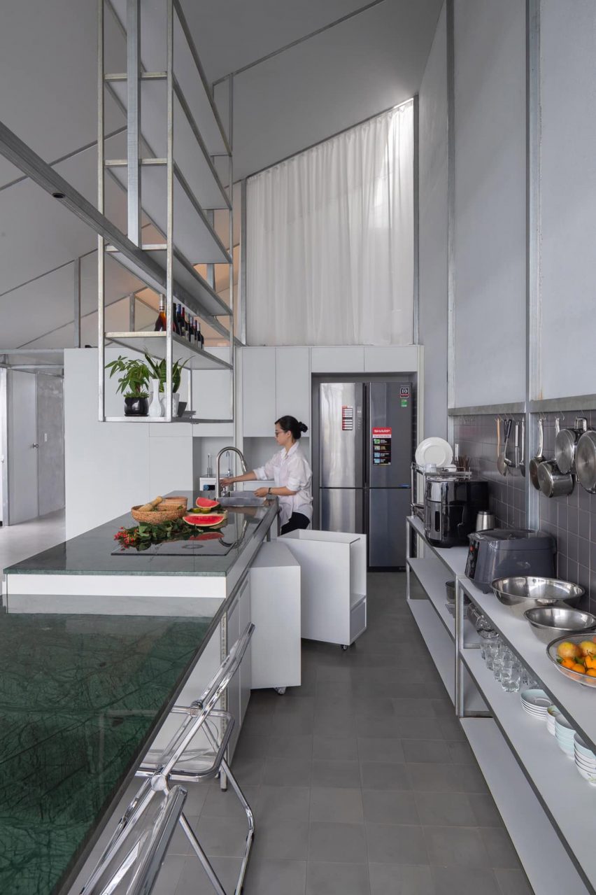 Mono-pitched steel kitchen with green marble table and overhead shelving