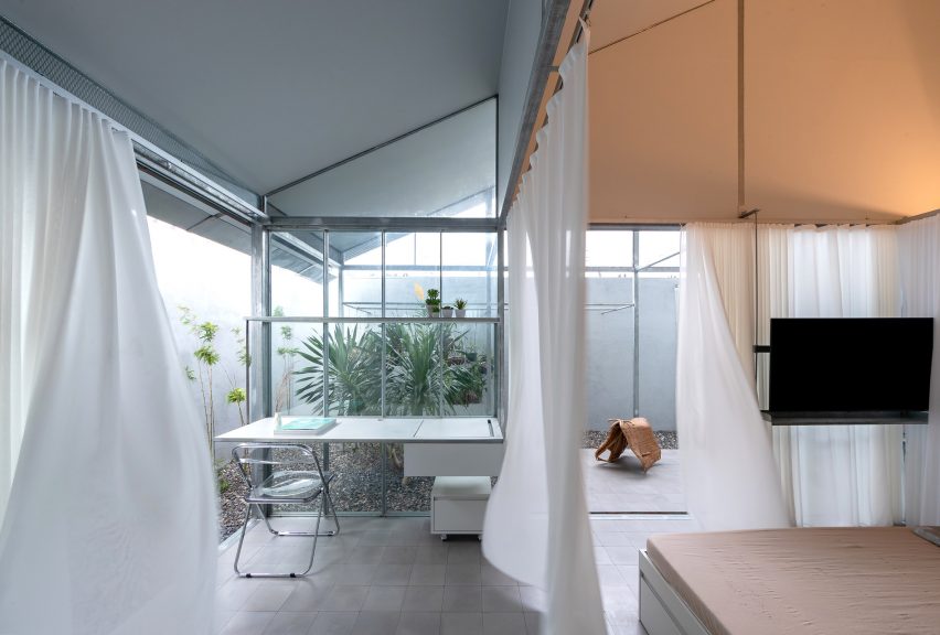 White curtains dividing interior office and living spaces in a mono-pitched structure