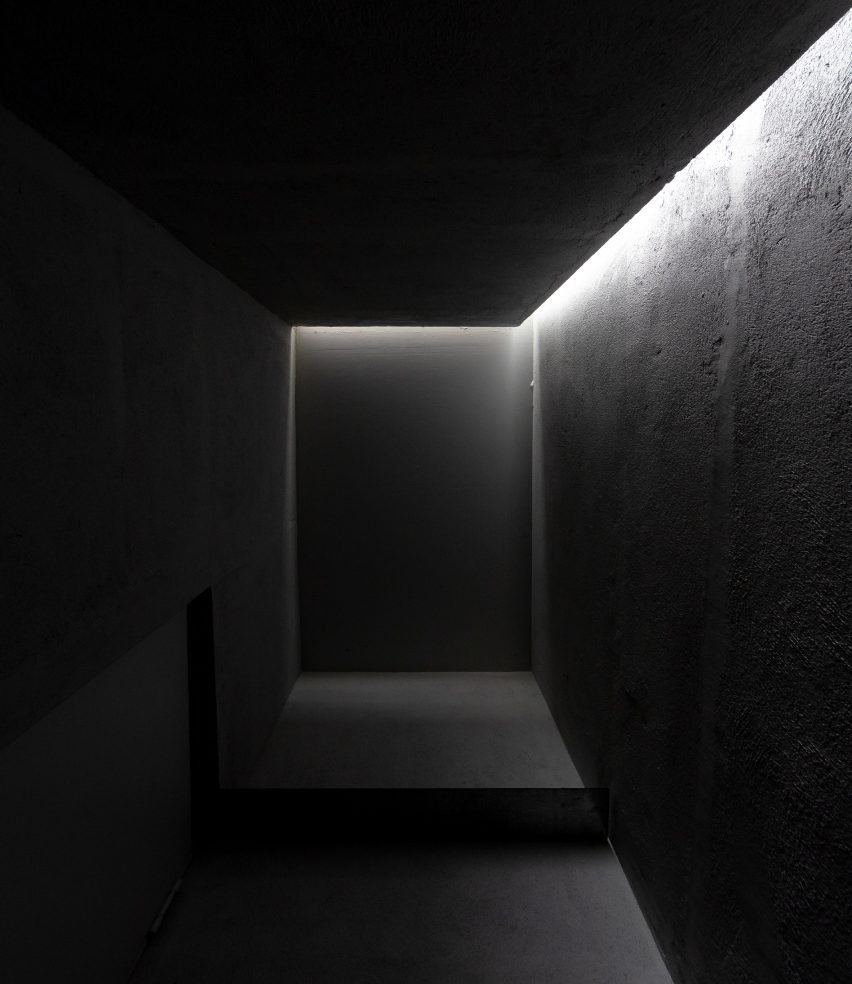 A dark rectangular space lit by an opening between the ceiling and wall