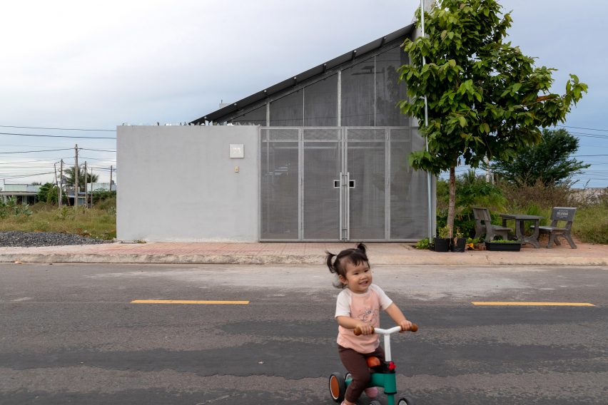 Exterior of a mono-pitched home by MIA Design Studio with a child playing on the street in front