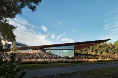 Wood, glass and stone building tucked into hillside