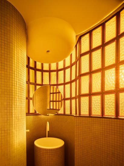 Amber light shining through original windows in apartment bathroom designed by Studio Noju