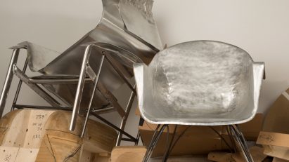 Silver armchair surrounded by a pile of metal material and wood scraps