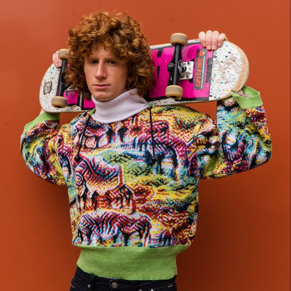Person wearing Cap_able's garment and holding a skateboard