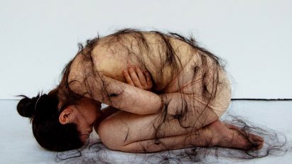 Image of a student draped in hair, which is part of an art project