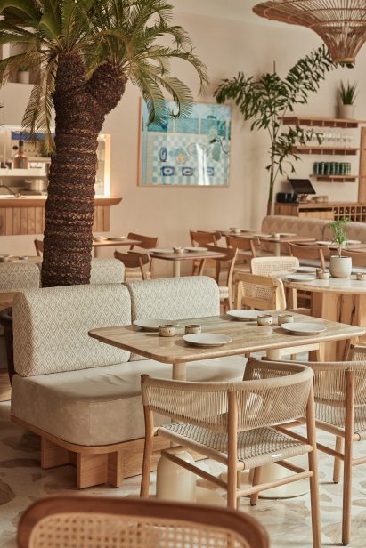 Dining table in Milk Beach Soho restaurant with a palm tree behind it