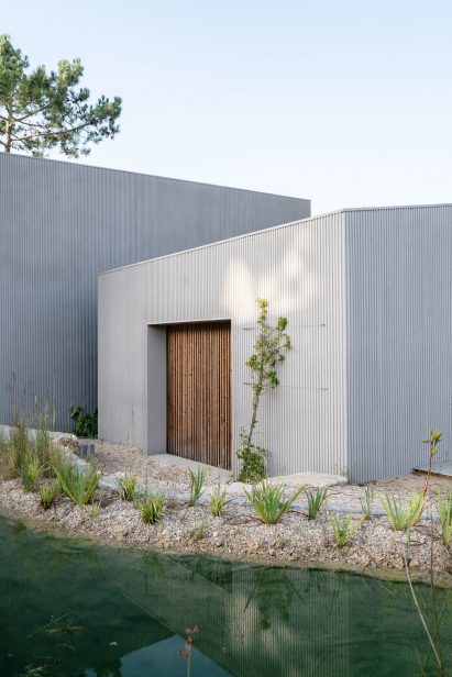Photograph of a house exterior with a natural swimming pool