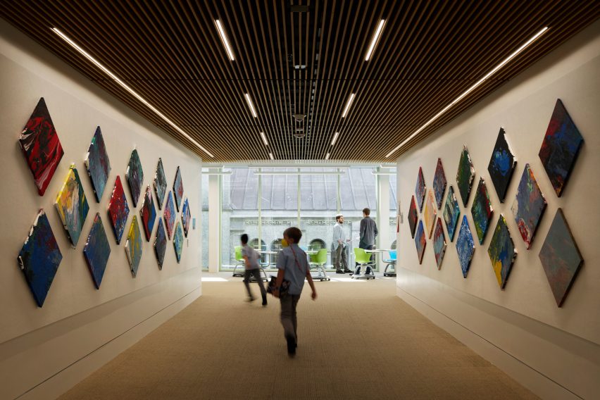 Interior of a wide school hallway with a window overlooking the roofline of a cathedral