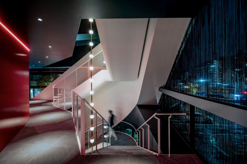 Circular space with lighting suspended in an opening between staircases
