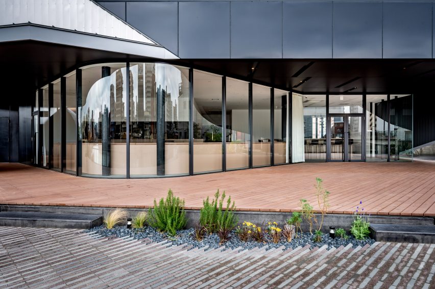 Paved entrance courtyard to a cultural building with curved glass walls