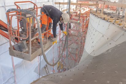 Photo of a construction worker installing carbon sheets onto the outer shell of a building before spraying it with concrete