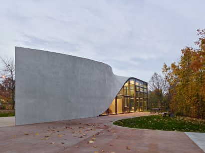 Photo of the side of Henn's Cube building, showing a smooth concrete facade that twists along its length to form a roof
