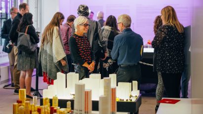 People gathered at a University of Calgary event with tables filled with architecture models