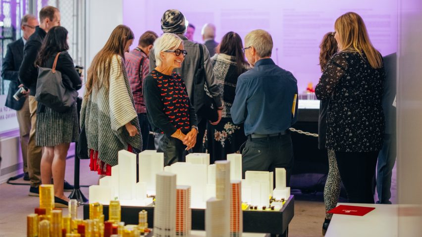 People gathered at a University of Calgary event with tables filled with architecture models