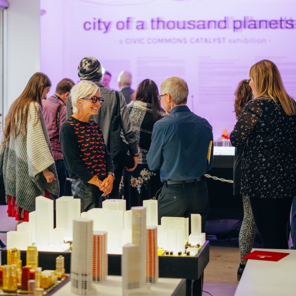 People gathered at a University of Calgary event with tables filled with architecture models