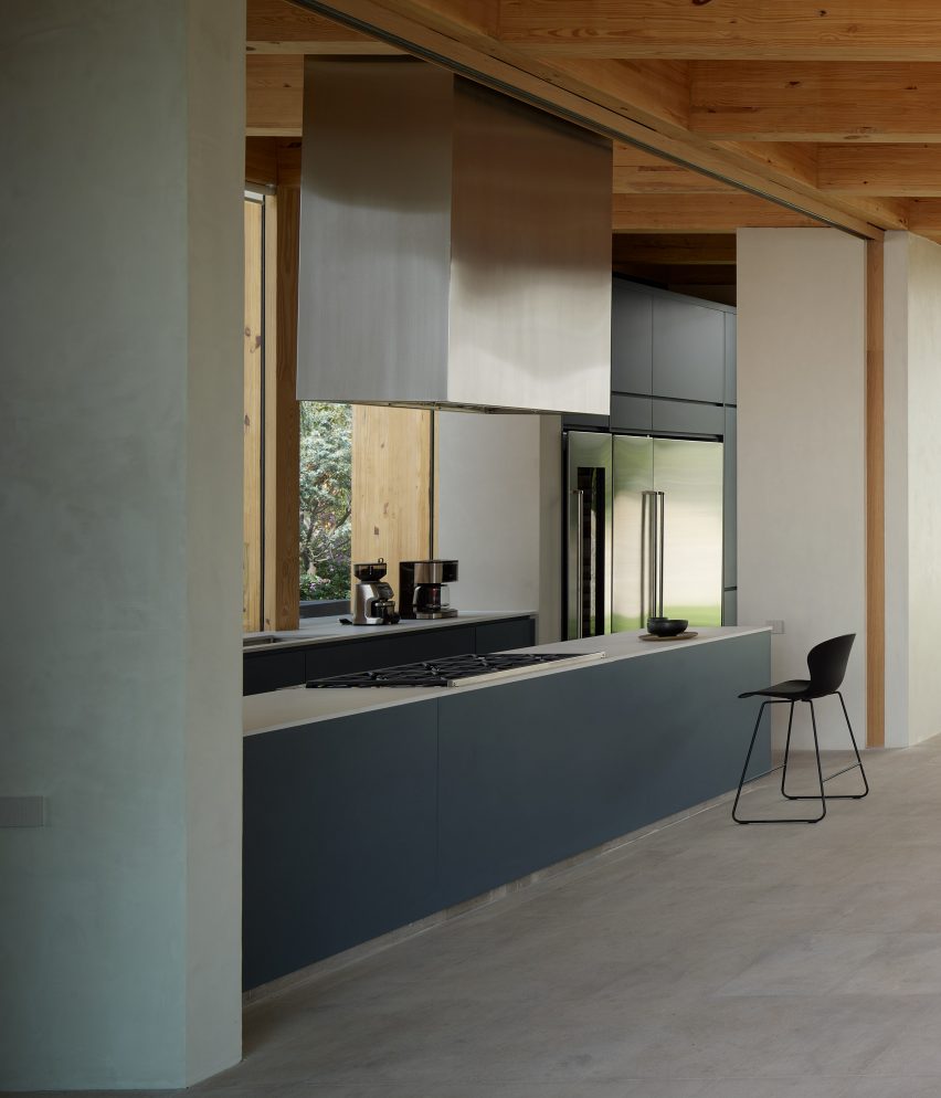 Open-plan kitchen with timber roof structure, silver extractor fan and blue kitchen cabinets