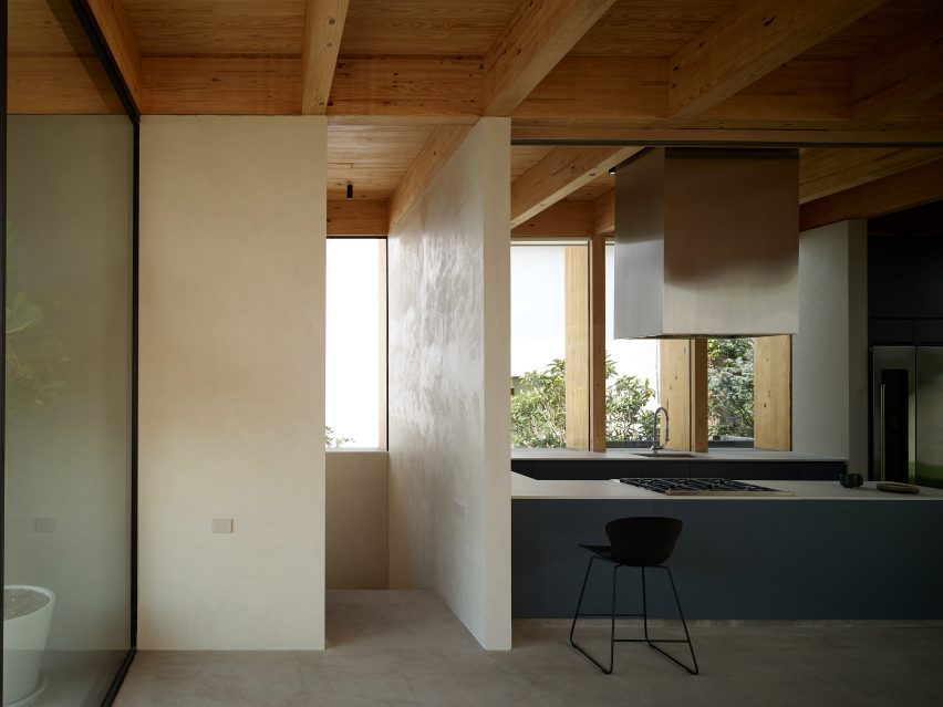 Open-plan kitchen with a timber roof structure and blue kitchen units