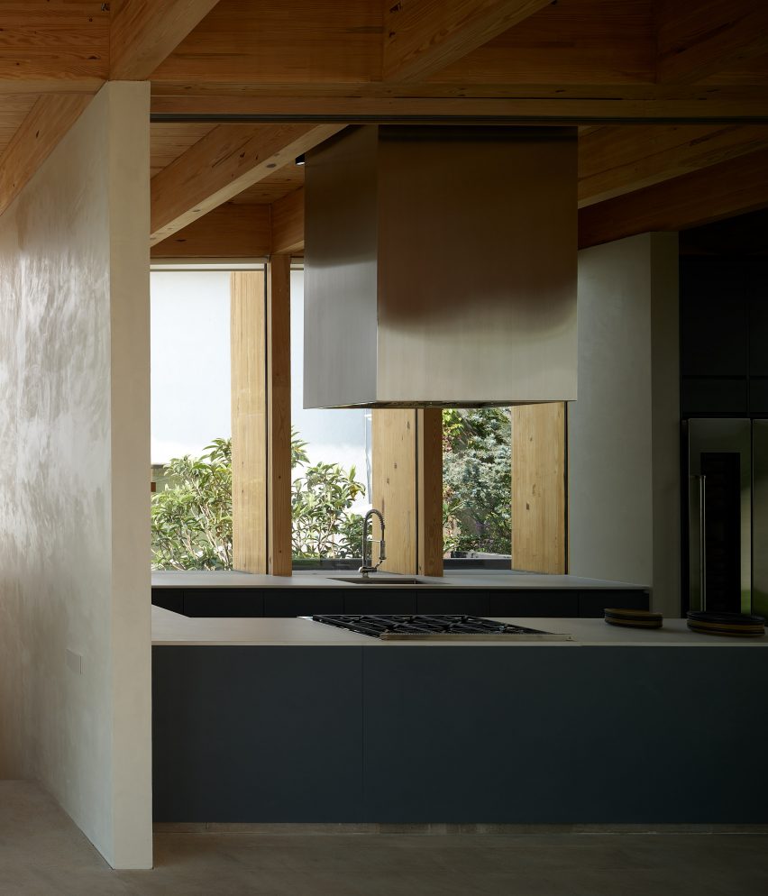 Open-plan kitchen with timber roof structure, silver extractor fan and blue kitchen cabinets