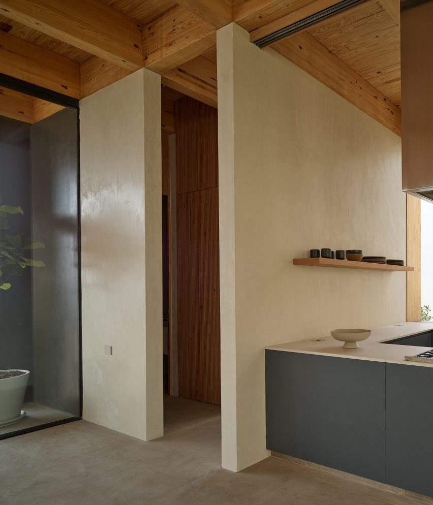 Open-plan kitchen with timber roof structure and blue kitchen cabinets
