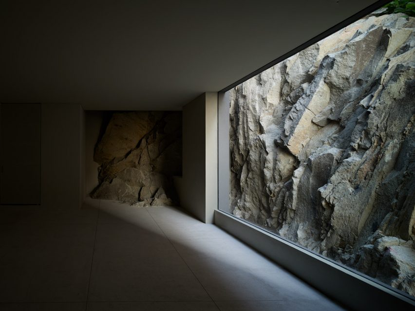 A dark empty room with floor-to-ceiling window looking onto rocky terrain