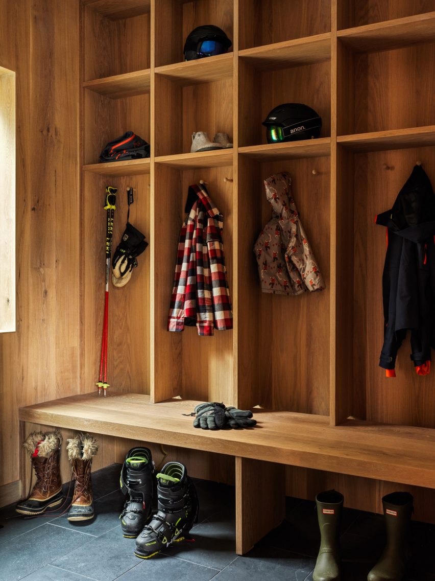 Timber-clad boot room with gridded wall storage for coats and hats