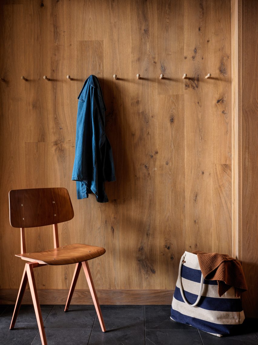 Wood-panelled wall with coat pegs and a wooden chair