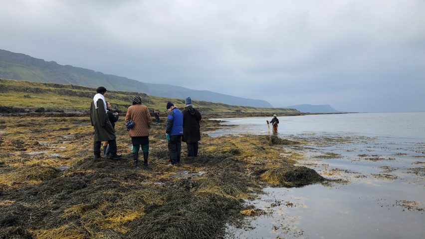 Figures standing in remote area beside body of water
