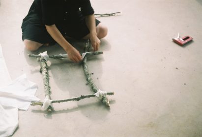 Person creating square shape made out of wooden sticks lashed together