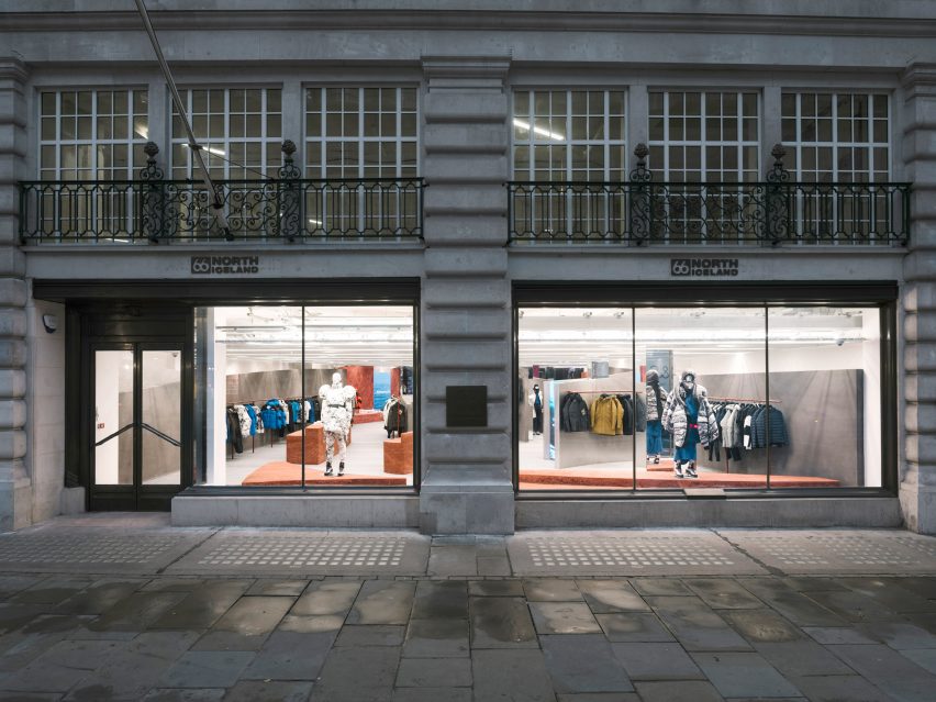 Shop front with stone facade and large window looking into a store with rammed-earth islands
