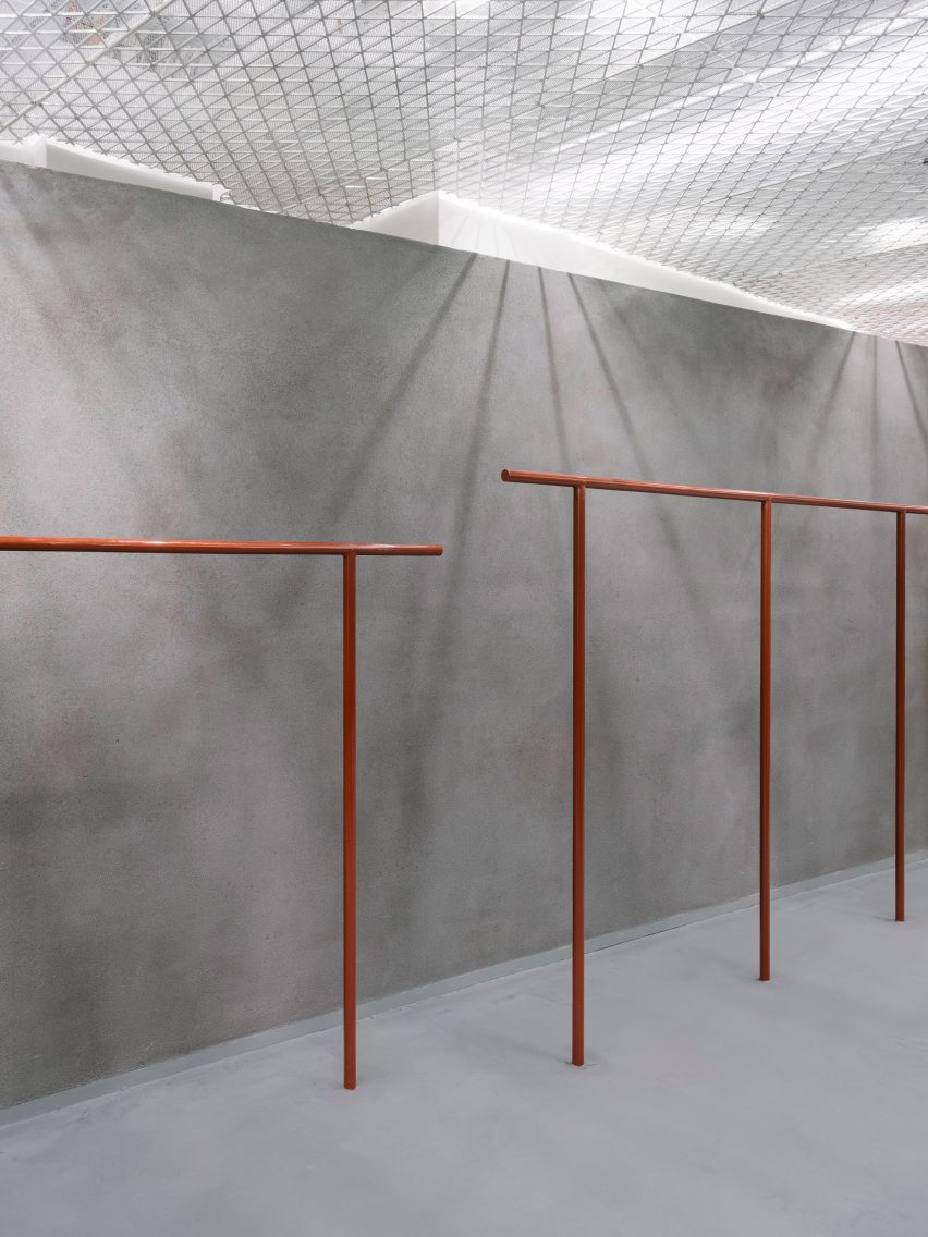 Grey shop interior with curved walls and orange clothes rails and hooks