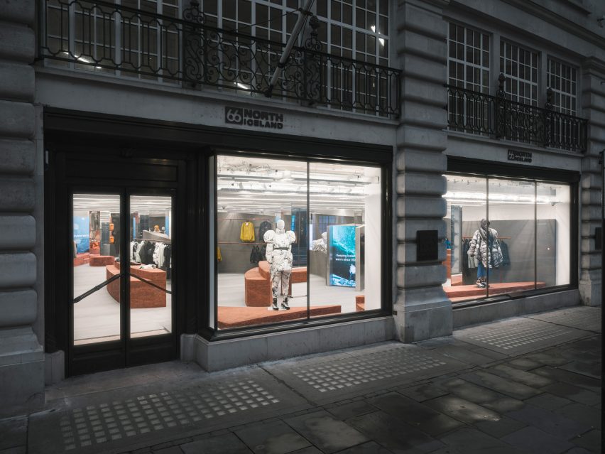 Stone facade with large windows showing a shop interior with rammed-earth islands