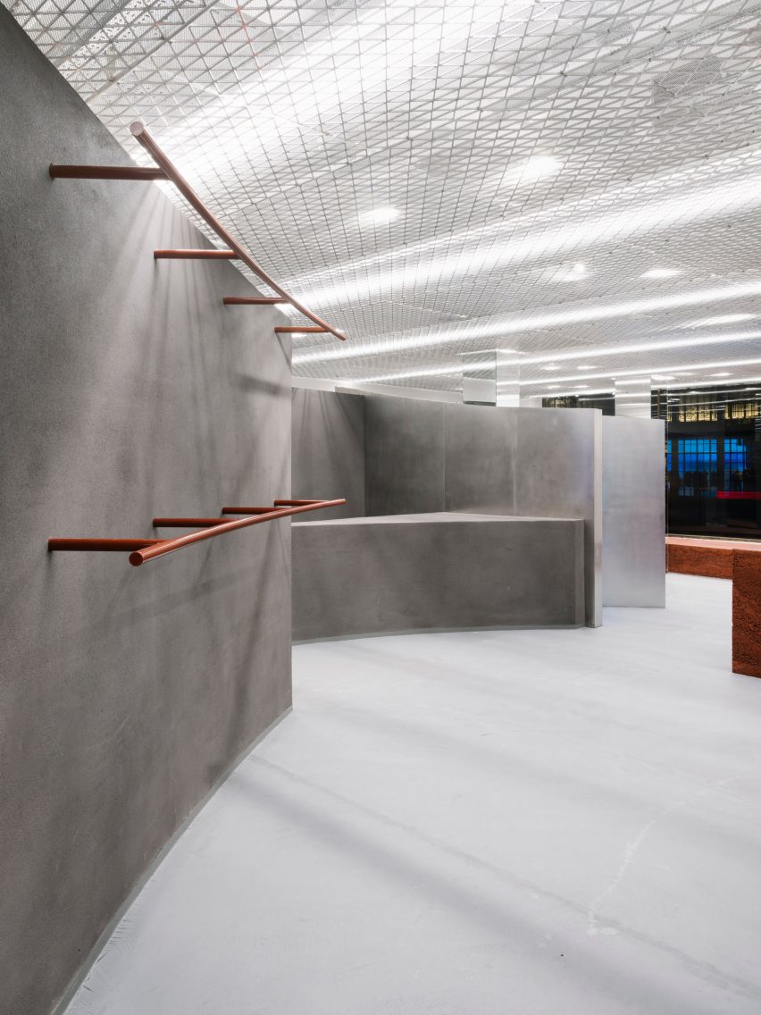 Grey shop interior with curved walls and orange clothes rails and hooks