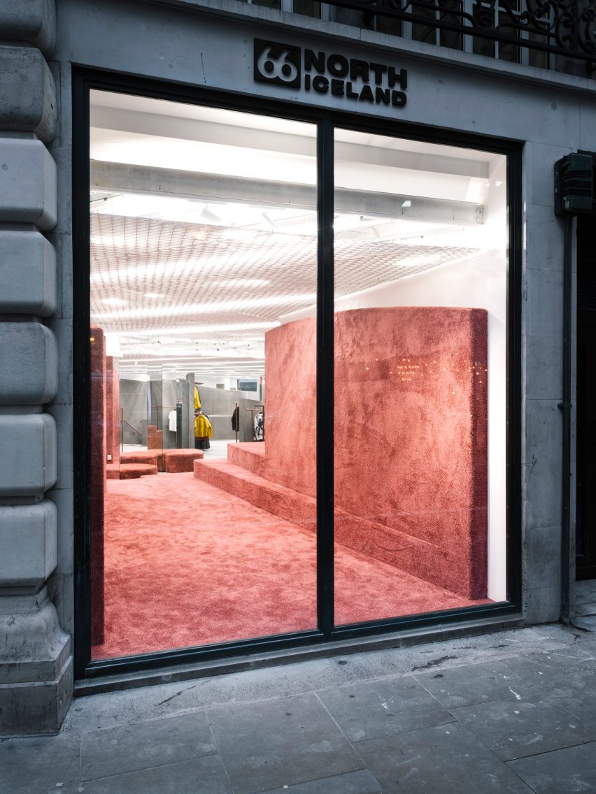 Large window looking into shop interior with a terracotta carpet covering on the floor and partition wall