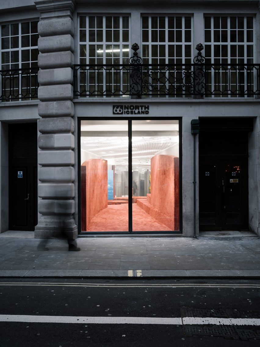 Shop front with stone facade and large window looking into a store with rammed-earth islands