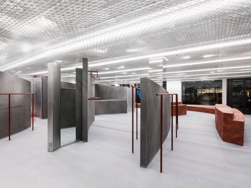 Grey shop interior with curved walls and orange clothes rails and hooks