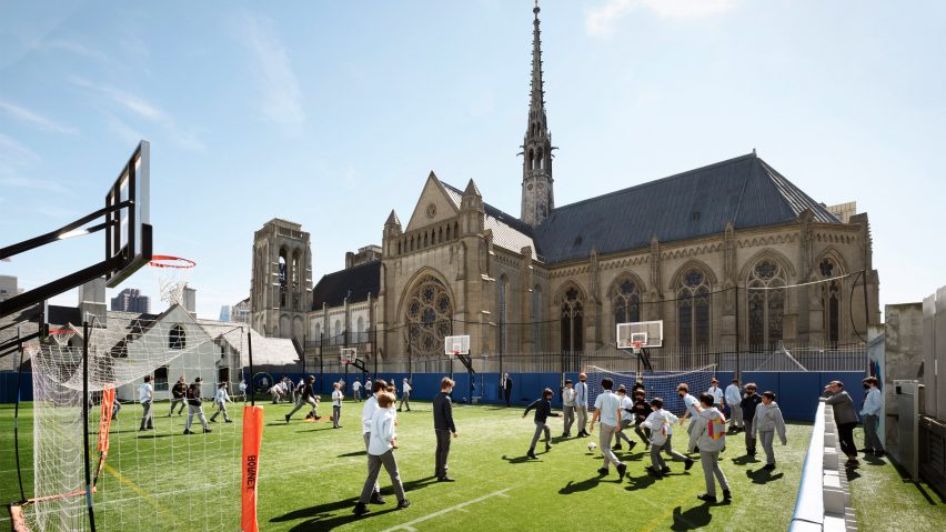Children playing on a football field with a cathedral in the background