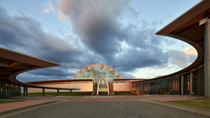 Circular outdoor space with curved overhanging roof at the perimeter and the First Americans Museum beyond