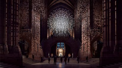Spherical installation made up of suspended piece of coal illuminated inside a cathedral