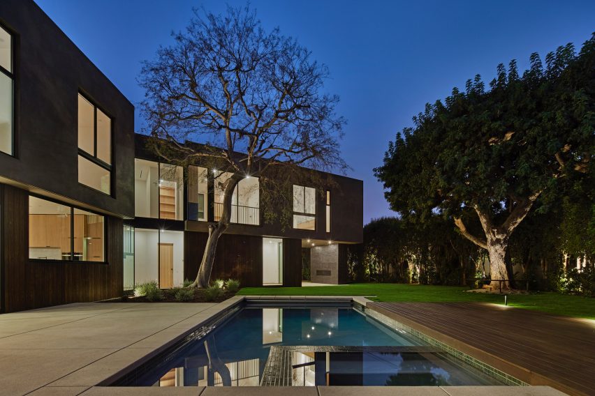Back garden and swimming pool of a stucco and ash-clad home